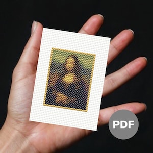 May include: A white canvas with a cross-stitch pattern of the Mona Lisa painting. The canvas is framed with a gold border. The canvas is held in a person's hand. The word "PDF" is written in grey on a grey circle.