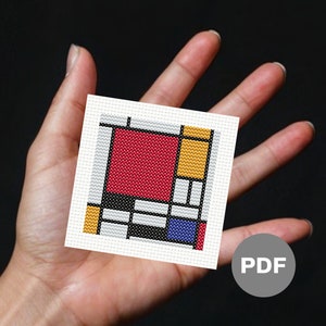May include: A cross-stitch pattern featuring a geometric design with squares in red, yellow, blue, black, and white. The pattern is on white fabric and is labeled "PDF".