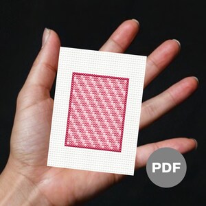 May include: A pink and white cross stitch pattern with a diagonal stripe design. The pattern is framed with a dark pink border. The pattern is on a white background. The pattern is labeled "PDF".