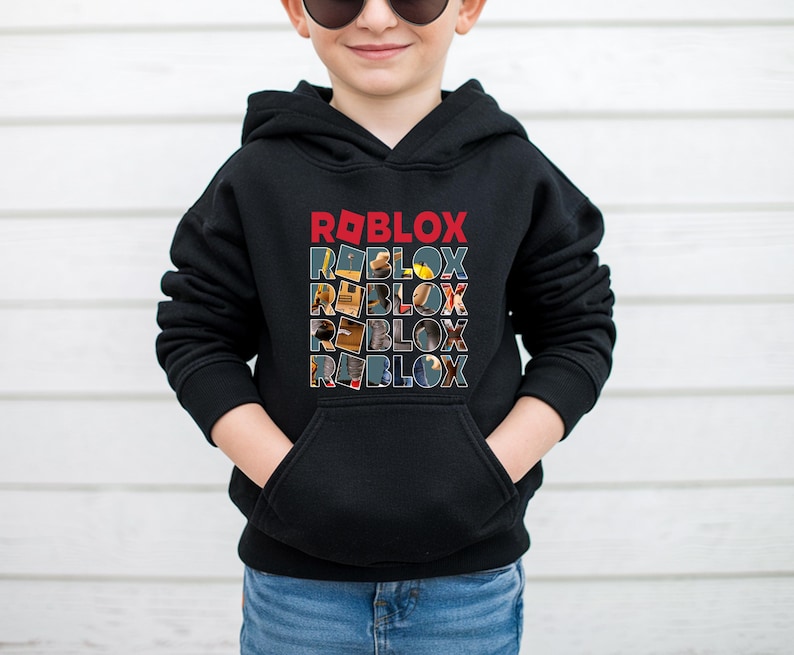 K&ouml;nnte beinhalten: Schwarzer Kapuzenpullover mit dem Wort "ROBLOX" in roten Blockbuchstaben &uuml;ber einem gestapelten Design desselben Wortes. Jeder Buchstabe im gestapelten Design enth&auml;lt ein anderes Bild. Der Pullover hat eine Vordertasche und wird von einer Person getragen.