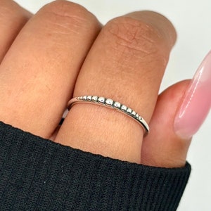 May include: A silver ring with a row of small beads.