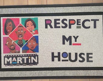 May include: Rectangular doormat with a black border and the words "RESPECT MY HOUSE". The mat features cartoon portraits of characters from the TV show "Martin" in colorful squares. The word "MARTIN" is also displayed.
