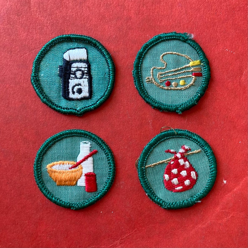 May include: Four green embroidered patches with white stitching. The patches feature a paint palette, a bottle of lotion, a bowl of batter, and a red and white polka dot bag.