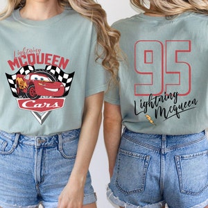 May include: Light blue t-shirt with a red race car graphic and the text "Lightning McQueen Cars". The back of the shirt has the number "95" and the text "Lightning McQueen".