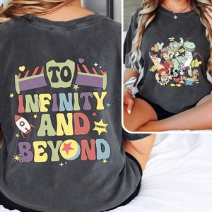 May include: A dark gray t-shirt with a colorful graphic print that says "To Infinity and Beyond" with a rocket and a star. The graphic is inspired by the Toy Story movie franchise.