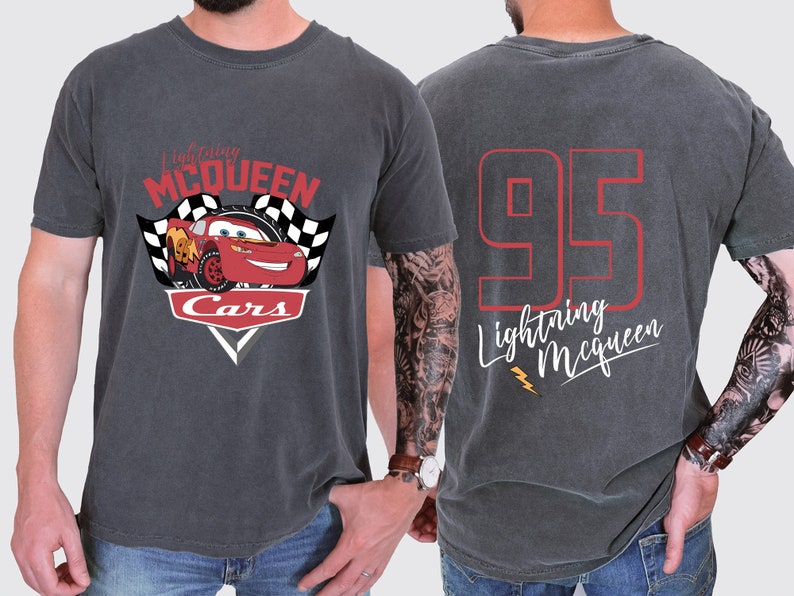 May include: A dark grey t-shirt featuring a red, white and black graphic of Lightning McQueen from the Cars movie. The back of the shirt has the number 95 in red with the text "Lightning McQueen" in white.