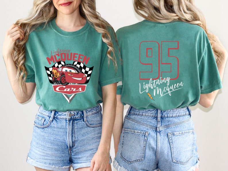 May include: A teal green t-shirt featuring a red and white graphic of Lightning McQueen from the Cars film. The back of the shirt has the number 95 and the text "Lightning McQueen" in white.