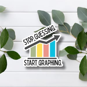 May include: A white sticker with the text "STOP GUESSING. START GRAPHING." features a bar graph with ascending colored bars and a black arrow. The sticker is surrounded by green leaves on a white wooden background.