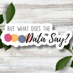 May include: A white sticker with the text "But what does the data say?" in black cursive font. Three colorful paint splatters are behind the text.