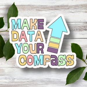 May include: A sticker with the text "MAKE DATA YOUR COMPASS" in colorful letters with an arrow pointing upwards. The arrow is made up of colorful stripes.