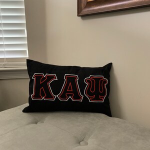May include: Black pillow with red and white embroidered letters spelling "&Kappa;&Alpha;&Psi;".