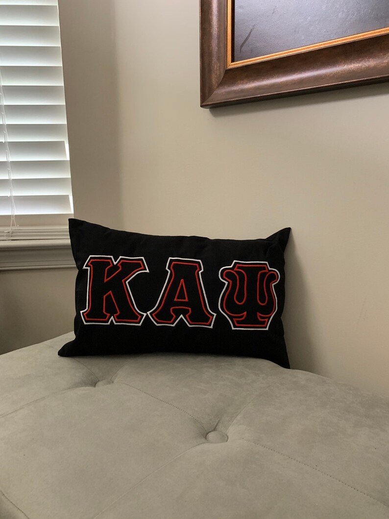 May include: Black pillow with red and white embroidered letters spelling "&Kappa;&Alpha;&Psi;".