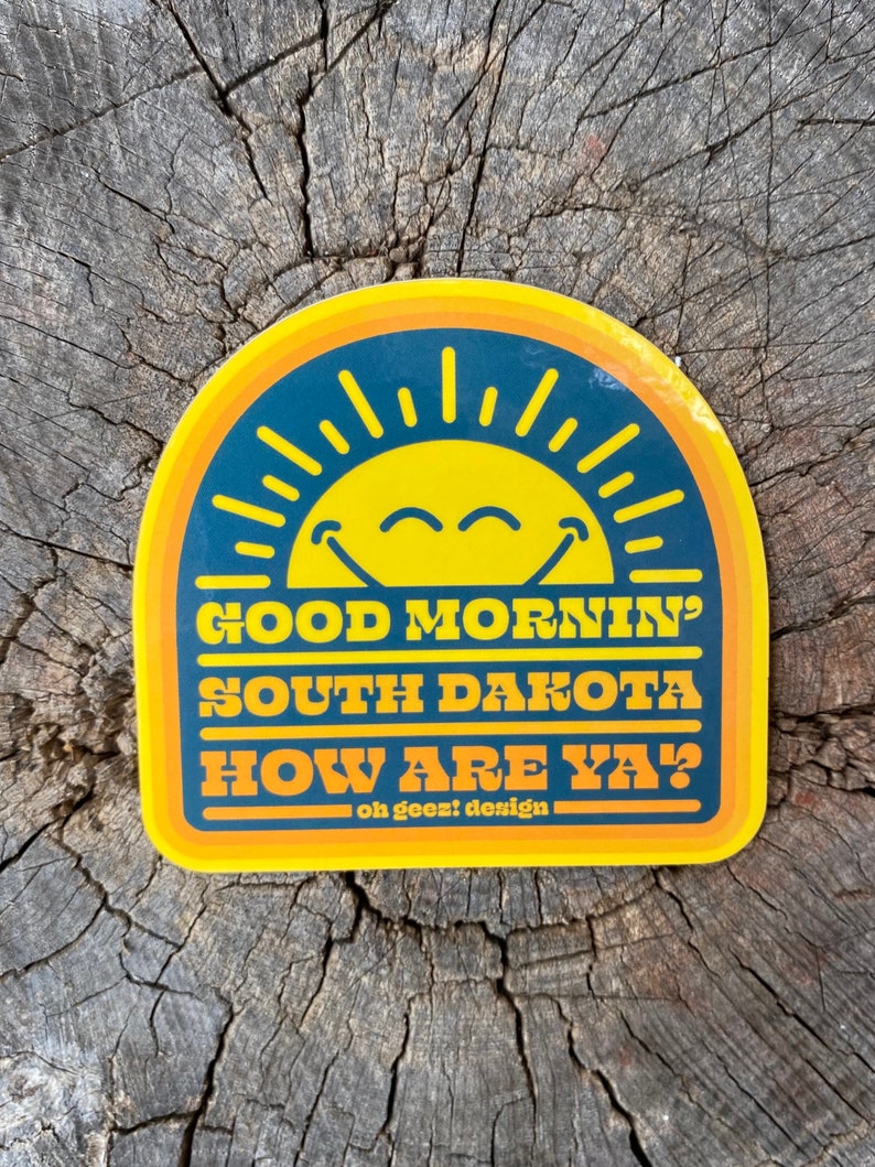 May include: Yellow and blue sticker with a smiling sun and the text "Good Mornin' South Dakota How Are Ya?" and "oh geez! design"