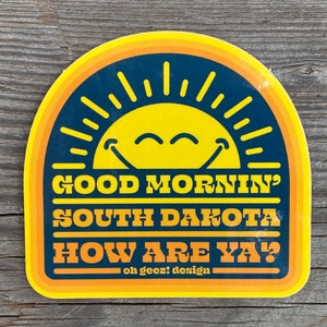 May include: Yellow and blue sticker with a smiling sun and the text "Good Mornin' South Dakota How Are Ya?"  - oh geez! design