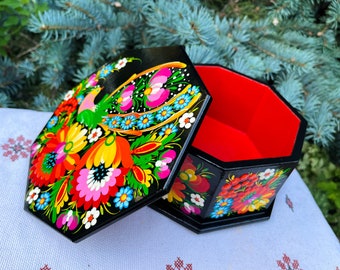 May include: A black wooden box with a hinged lid, painted with colourful flowers and a bird. The inside of the box is red.