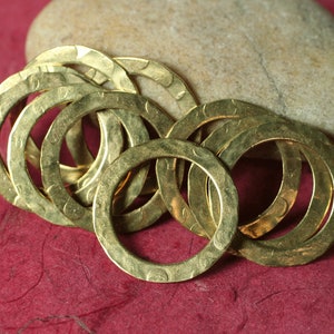 May include: A group of gold-colored metal rings with a hammered texture. The rings are arranged in a pile, with some overlapping.