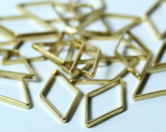 May include: A collection of small, gold-colored diamond-shaped metal frames. The frames are arranged in a scattered pattern, with some overlapping. The metal has a shiny finish, reflecting light. These components could be used for jewelry making or other craft projects.