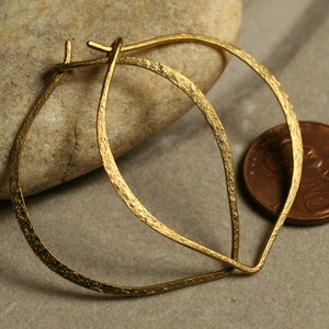 May include: A pair of gold hoop earrings with a hammered texture. The earrings are about the size of a US penny.