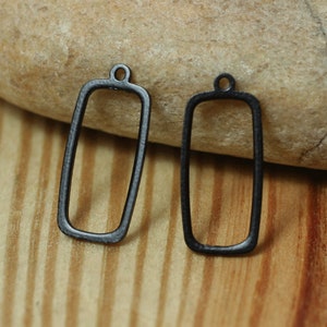 May include: Two dark grey rectangular pendant charms with a small loop at the top for attaching to a chain or other jewellery component. The charms are made of metal and have a simple, minimalist design.