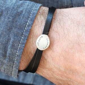 K&ouml;nnte beinhalten: Ein schwarzes Lederarmband mit einem silbernen Anh&auml;nger, auf dem "Mein Held, mein Papa" steht.