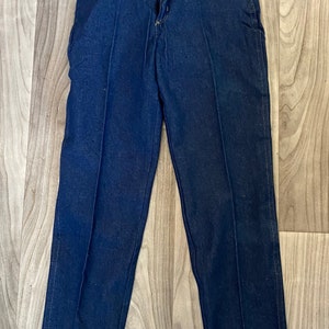 May include: A pair of dark blue denim jeans with a straight leg fit. The jeans have a classic five-pocket style and a button fly.