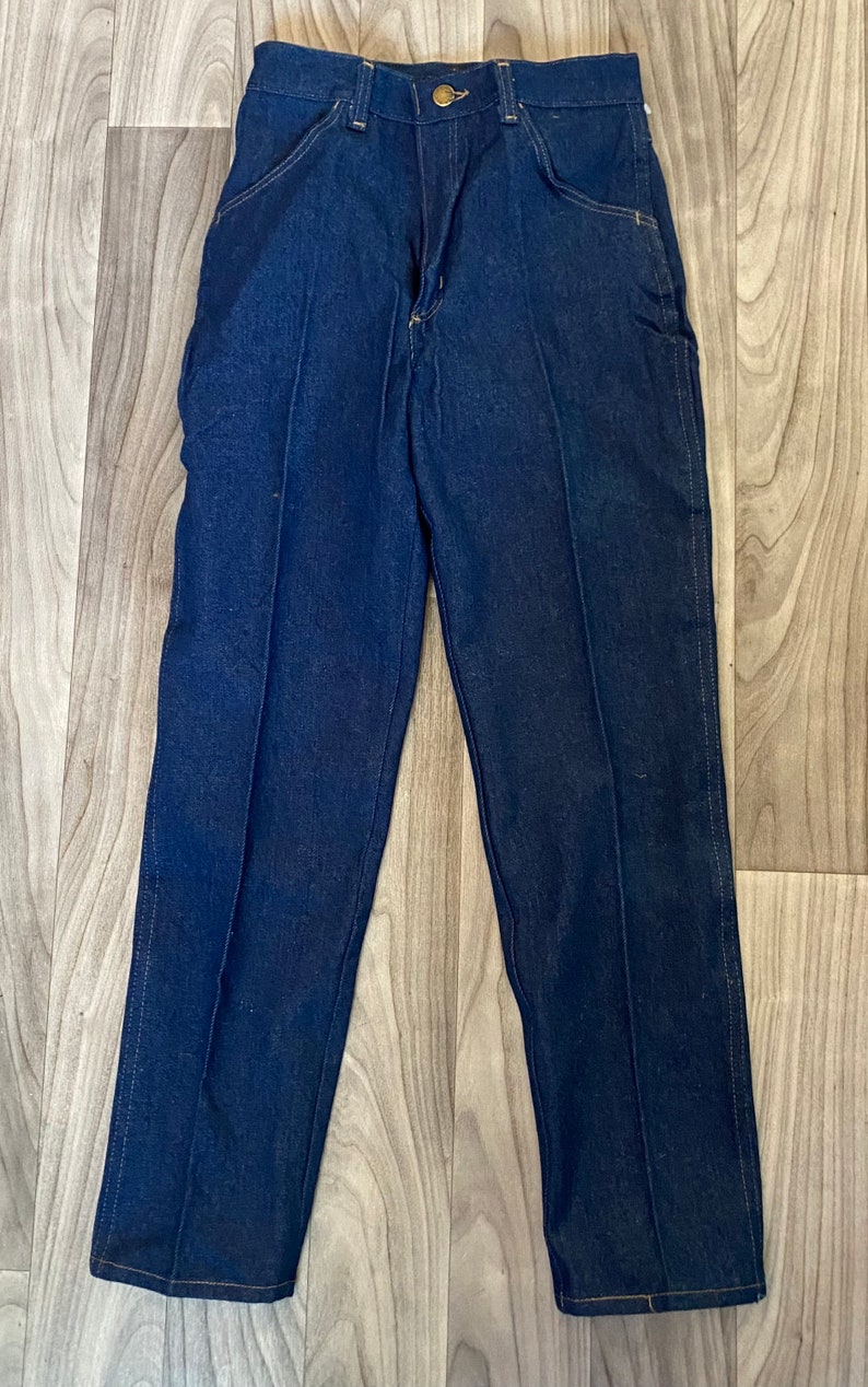 May include: A pair of dark blue denim jeans with a straight leg fit. The jeans have a classic five-pocket style and a button fly.