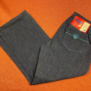K&ouml;nnte beinhalten: Eine dunkelblaue Jeanshose mit einem blauen und wei&szlig;en Stickmuster auf der Ges&auml;&szlig;tasche. Die Hose hat einen Bund mit einem Etikett, auf dem "Wonder Kid" und "Gr&ouml;&szlig;e 4T" steht.