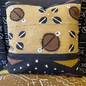 May include: A brown and black patterned throw pillow with white accents. The pillow is made of a woven fabric and has a geometric design.