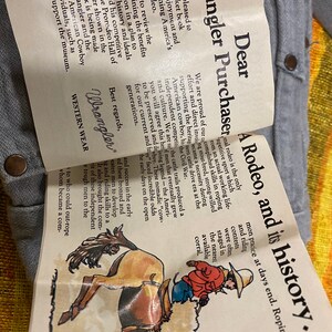 Puede incluir: Un folleto vintage de Wrangler con una ilustraci&oacute;n colorida de un vaquero montando un bronco salvaje. El texto de la portada dice "Estimado comprador de Wrangler, Un rodeo, y su historia..."