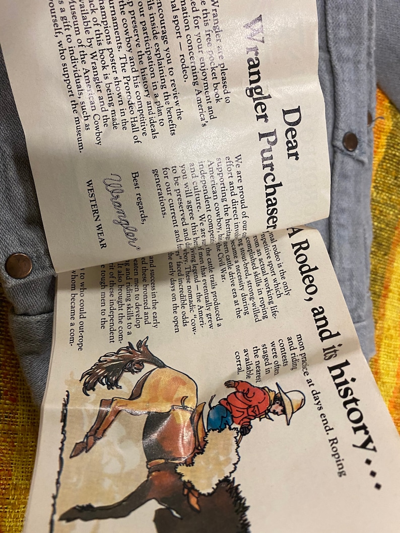 Puede incluir: Un folleto vintage de Wrangler con una ilustraci&oacute;n colorida de un vaquero montando un bronco salvaje. El texto de la portada dice "Estimado comprador de Wrangler, Un rodeo, y su historia..."
