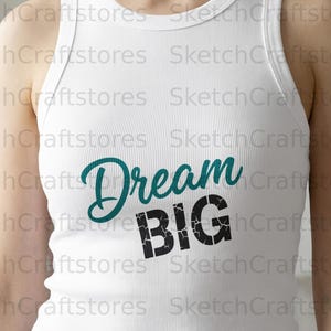 Peut inclure: Débardeur blanc côtelé avec le texte sarcelle "Dream" en cursive et le texte noir "BIG" en gras. Le débardeur est de style sans manches.