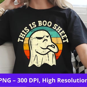 Puede incluir: Camiseta negra con un gráfico de fantasma gruñón dentro de un diseño circular con el texto "THIS IS BOO SHEET". El diseño utiliza una paleta de colores retro. Un diseño divertido y espeluznante para Halloween.