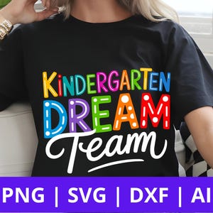 以下が含まれることがあります： カラフルなアウトライン文字で「Kindergarten Dream Team」と書かれた黒いTシャツ。テキストの下には、PNG、SVG、DXF、AIのファイルタイプを示す紫色のバナーがあります。