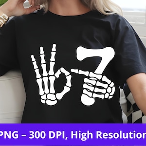 May include: Black t-shirt with a white skeleton hand graphic forming the OK symbol and the number 7. The graphic is a humorous design. The shirt is a high-resolution PNG image.