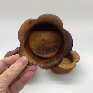 May include: Three wooden bowls, each with a flower-shaped design. The bowls are crafted from dark brown wood and have a smooth, polished surface. These small bowls are ideal for serving dips, sauces, or small snacks.