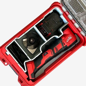 Può includere: Una valigetta per attrezzi Milwaukee rossa con un inserto in schiuma grigia. La valigetta contiene un utensile multifunzione Milwaukee, una batteria e una lama da taglio.