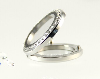 May include: Open silver locket with a clear glass window. The locket's rim is adorned with small, sparkling crystals. The words "LOCKET LOVE" are printed at the bottom of the image.