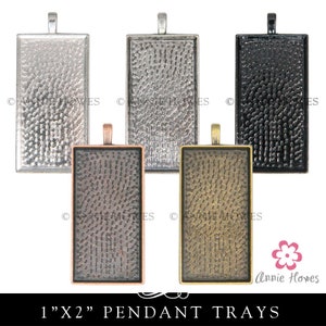 May include: Five pendant trays in different metal finishes: silver, antique silver, black, copper, and antique brass. Each tray is 1 inch by 2 inches and has a textured surface. The trays are perfect for creating custom jewelry.