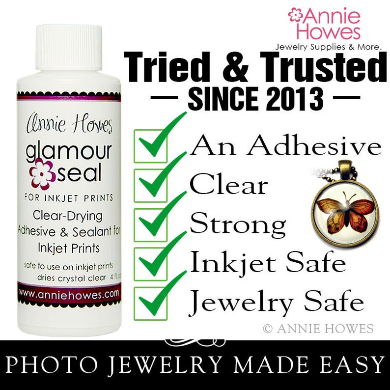 May include: A clear bottle of Annie Howes Glamour Seal adhesive for inkjet prints. The bottle is labeled with the text "Annie Howes Glamour Seal" and "For Inkjet Prints". The bottle is surrounded by green check marks with the text "An Adhesive", "Clear", "Strong", "Inkjet Safe", and "Jewelry Safe".