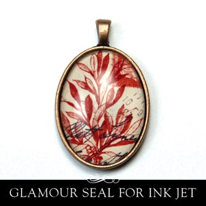 May include: A copper oval pendant with a glass insert featuring a red floral design on a white background. The pendant has a loop at the top for hanging.