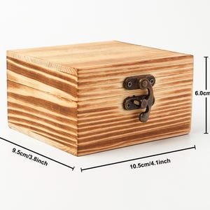 May include: A small, square wooden box with a hinged lid and a metal clasp. The box is made of light brown wood with darker brown grain patterns. It measures 4.1 inches long, 3.8 inches wide, and 2.4 inches high.