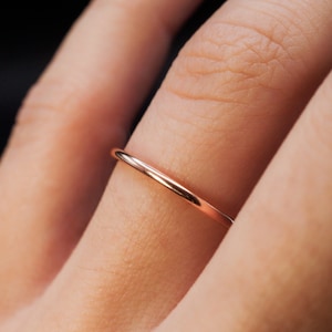 Op de afbeelding: Een dunne, roségouden ring gedragen aan een vinger.