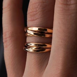 Pu&ograve; includere: Un anello d'oro con tre bande intrecciate. Le bande sono lisce e lucenti.