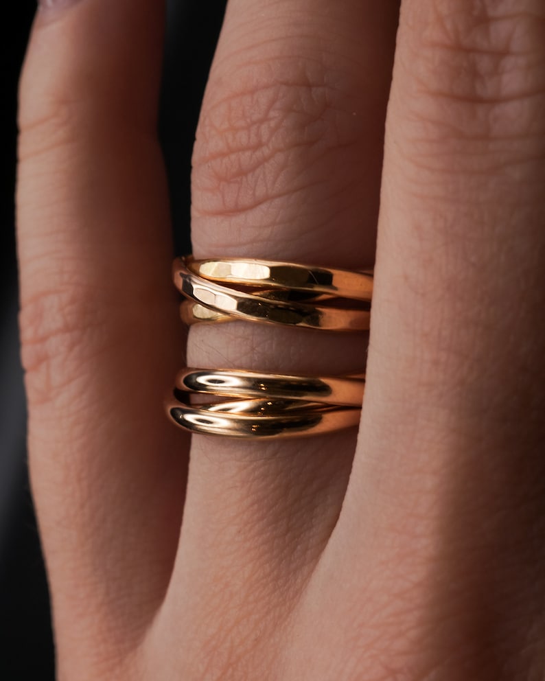 Pu&ograve; includere: Un anello d'oro con tre bande intrecciate. Le bande sono lisce e lucenti.