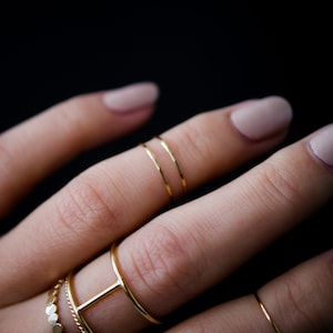 Ultra Thin Stacking Ring worn as midi knuckle rings in the hammered finish. Paired with Large Cage Ring, Thin Twist Ring and the Original Bead Ring.