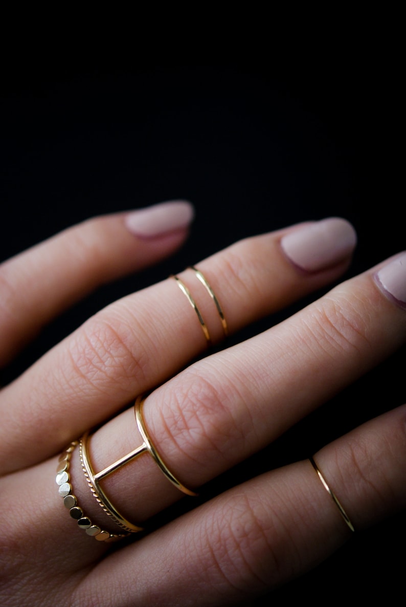 Ultra Thin Stacking Ring worn as midi knuckle rings in the hammered finish. Paired with Large Cage Ring, Thin Twist Ring and the Original Bead Ring.