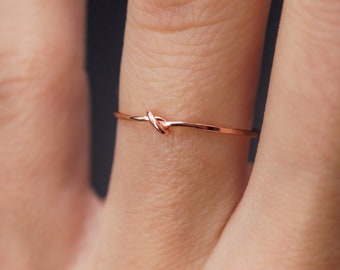 Op de afbeelding: Een dunne roségouden ring met een knoopdesign.