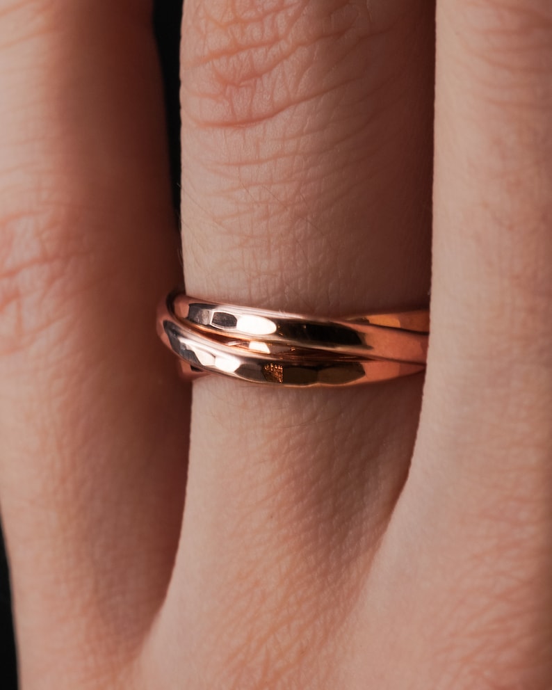 Pu&ograve; includere: Primo piano di un anello in oro rosa con finitura martellata. L'anello &egrave; indossato su un dito.