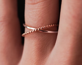 May include: Two gold rings, one with a twisted rope design, worn on a finger.