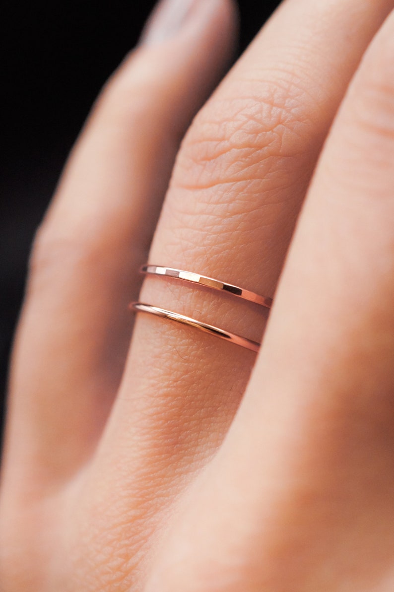 K&ouml;nnte beinhalten: Nahaufnahme von zwei zarten ros&eacute;goldenen Ringen. Der obere Ring hat ein facettiertes Design, w&auml;hrend der untere Ring glatt ist. Die Ringe befinden sich an einem Finger und zeigen ihren minimalistischen und eleganten Stil. Ideal f&uuml;r den t&auml;glichen Gebrauch oder als besonderes Geschenk.